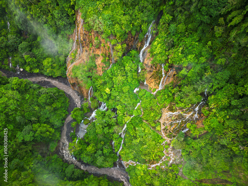 A stunning waterfall located in the center of a lush green forest photo