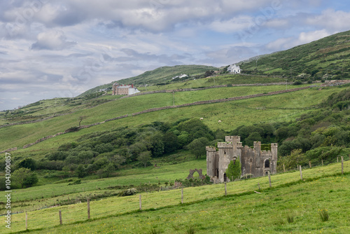 A view of Clifden Castle in Connemara, Ireland, surrounded by lush, green hills and rural farmlands photo