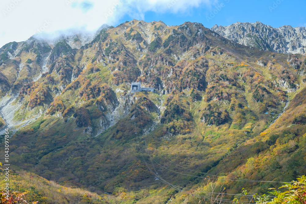 Obraz premium Kurobedaira Station, Tateyama, Toyama, Chubu, Japan, Lush green mountains display vibrant foliage, with rocky peaks under a bright blue sky
