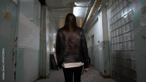 man with long hair moves through a long corridor