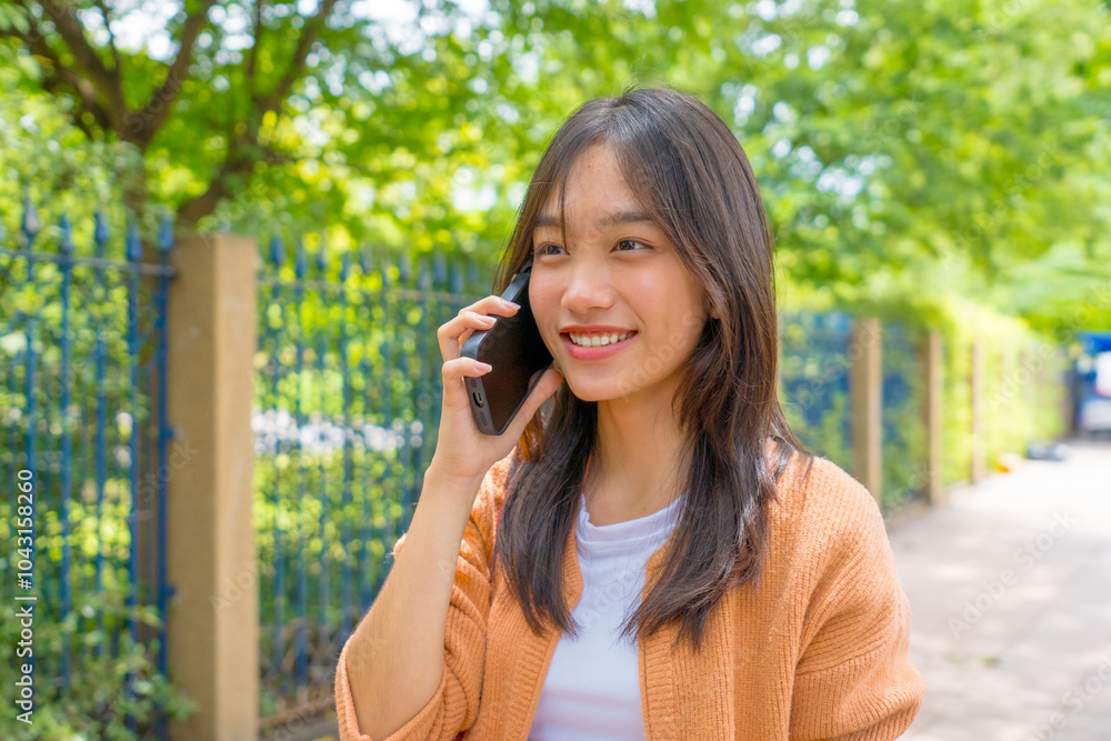Asian young woman talking on cellphone smiling laughing while walking outdoors in city. Asian young woman talking on cellphone smiling laughing while walking outdoors in city.