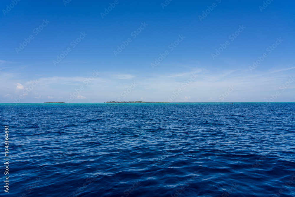 Obraz premium Mataking Island and Small Mataking Island (Pulau Mataking Kecil) on the horizon, from a far distance with multiple groups of tourists snorkelling and scuba diving.