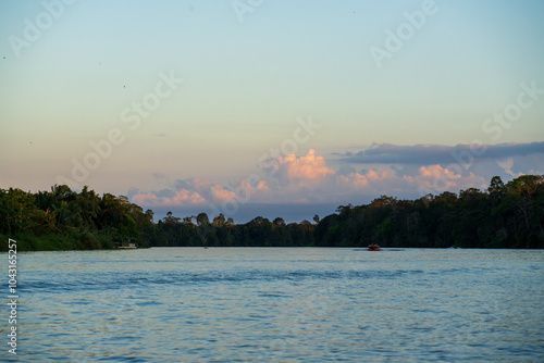 River cruise jet boats touring the Kinabatangan River, Sandakan, Sabah, Malaysia (Borneo) at Sunset with red orange sunlight in clouds.