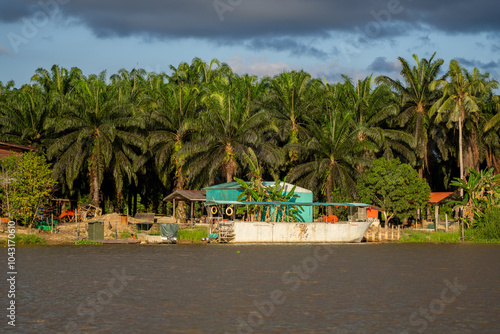 Boats and houses of Sukau Village (Kampung Sukau) on the banks of the Kinabatangan River, Sabah, Malaysia (Borneo) at midday. photo