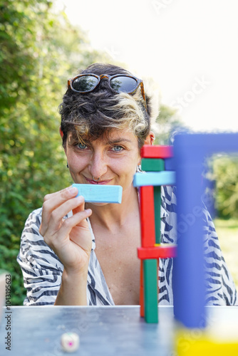 Non-binary person playing with colorful blocks outdoors photo