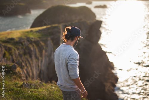 Young man enjoying sunset at Asturian cliffs photo