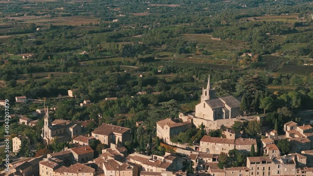 Aerial retreating pan up view of Bonnieux, Provence, France, highlighting the village’s scenic rooftops and countryside landscape