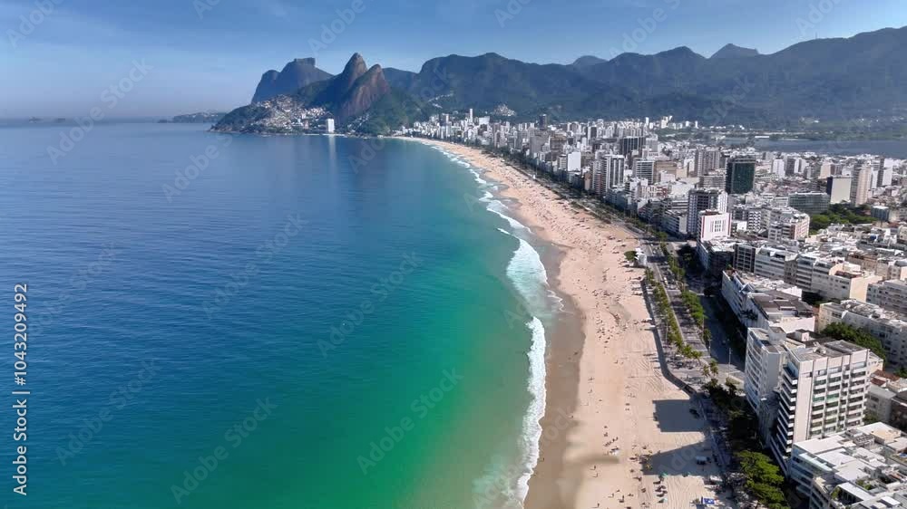 Drone flies backward, ascending over Ipanema Beach and Pedra do Arpoador, ocean, skyscrapers, and mountains - Rio de Janeiro Drone flies backward, ascending over Ipanema Beach and Pedra do Arpoador, ocean, skyscrapers, and mountains - Rio de Janeiro