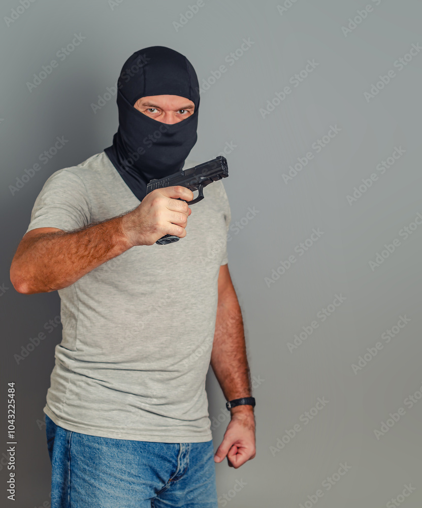 Dangerous criminal man holding gun threatening. Robber in black balaclava aiming gun at victim. Dangerous criminal man holding gun threatening. Robber in black balaclava aiming gun at victim.