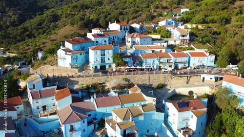 Drone flight over Juzcar, the Smurf village with a lot of bluewashed houses and mountains in the background located in southern Spain.  photo