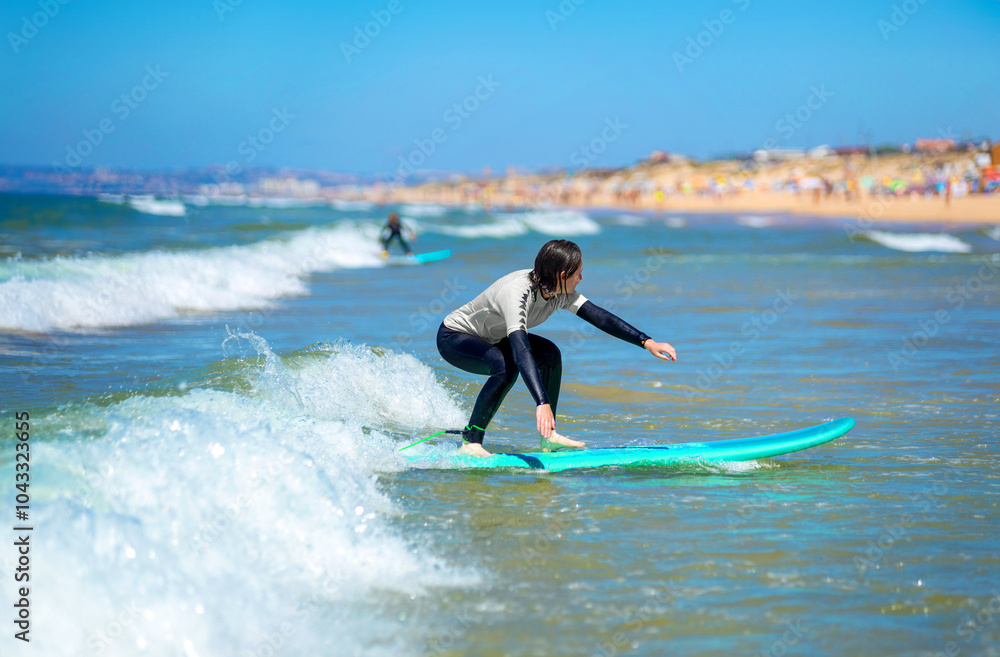 Teenage girl learning to surf on foam in the ocean. First surfing lesson. Amateur surfer. Surfing training. Photo for surfing school advertising on social media. Teenage girl learning to surf on foam in the ocean. First surfing lesson. Amateur surfer. Surfing training. Photo for surfing school advertising on social media.