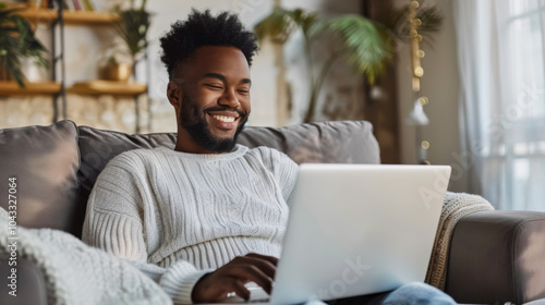 Smiling man using laptop while relaxing at home