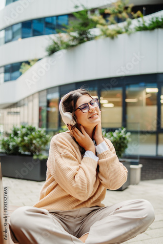 Young caucasian woman listening to music or audiobook outdoors