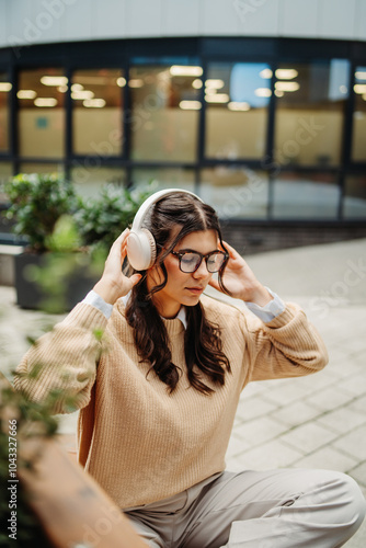 Young caucasian woman listening to music or audiobook outdoors