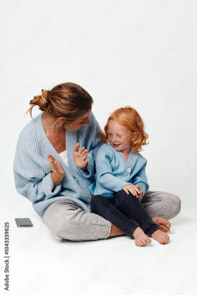 Mother and daughter sitting together holding hands in a moment of love and connection on the floor Mother and daughter sitting together holding hands in a moment of love and connection on the floor