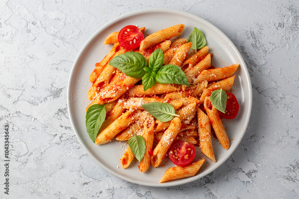 Classic italian pasta penne alla arrabiata with basil and freshly grated parmesan cheese on dark table. Penne pasta with chili sauce arrabbiata.