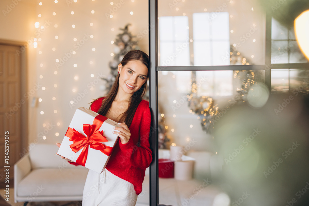 Woman Holding Holiday Gift in Festive Room with Lights Woman Holding Holiday Gift in Festive Room with Lights
