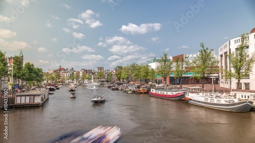 Boats floating and passing by near the National Opera music and theatre venue timelapse. Houseboats on the river in Amsterdam under a cloudy sky. Popular tourist destination in the Netherlands photo