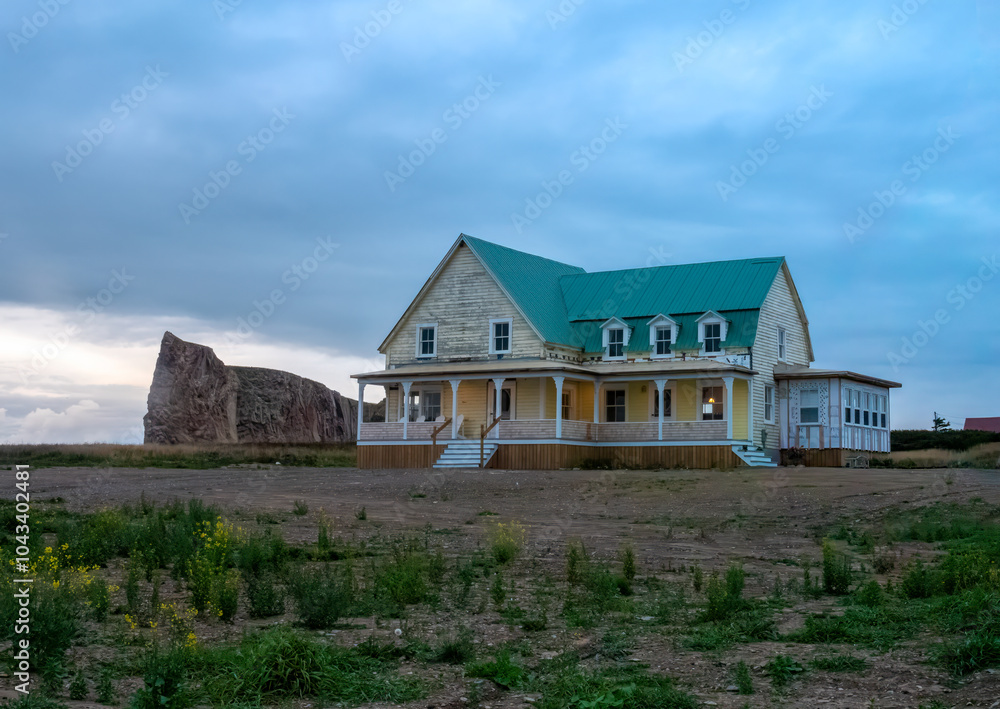 Old wooden houses at the edge of a cliff in the village of Percé with the iconic offshore rock formation in the background, Gaspésie peninsula, Quebec, Canada Old wooden houses at the edge of a cliff in the village of Percé with the iconic offshore rock formation in the background, Gaspésie peninsula, Quebec, Canada