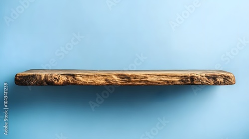 Rustic wooden table against light blue background. Empty tabletop with natural grain texture, minimalist display setup, strong horizontal lines.