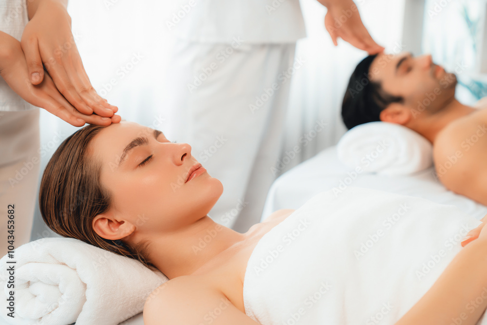 Caucasian couple enjoying relaxing anti-stress head massage and pampering facial beauty skin recreation leisure in dayspa modern light ambient at luxury resort or hotel spa salon. Quiescent Caucasian couple enjoying relaxing anti-stress head massage and pampering facial beauty skin recreation leisure in dayspa modern light ambient at luxury resort or hotel spa salon. Quiescent