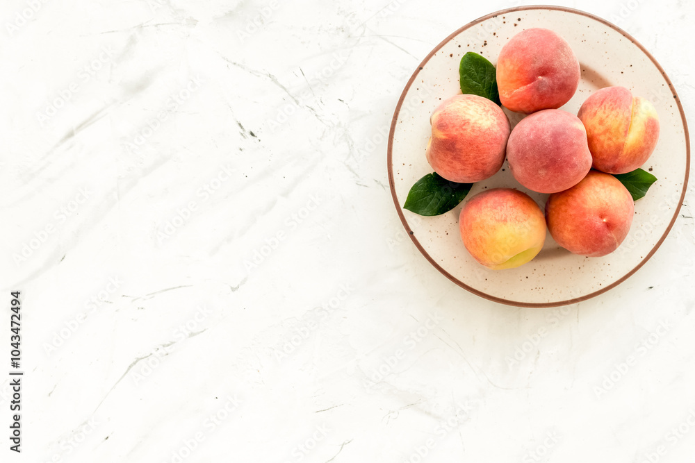 Summer fruits. Ripe red peaches on plate on white table top-down copy space Summer fruits. Ripe red peaches on plate on white table top-down copy space