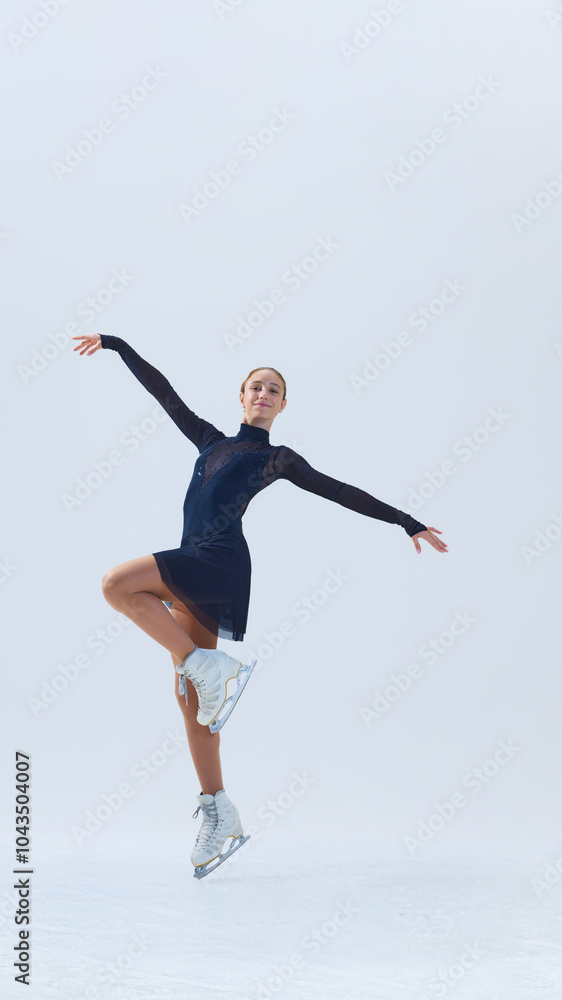 Obraz premium Vertical image. Beautiful and talented young girl, figure skater in motion on rink, performing with elegance and grace, isolated on white background. Concept of sport, performance. Copy space, ad