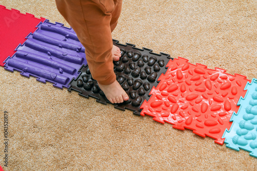 The child is walking on the puzzle sensory play orthopedic mats. Good for health and feet development. Funny play with a healthy benefit. 
