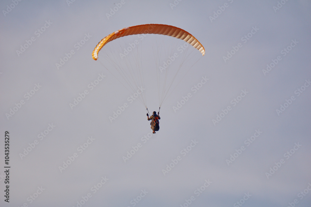 A paraglider flies over the sea and mountains during sunset. Extreme sports and adrenaline A paraglider flies over the sea and mountains during sunset. Extreme sports and adrenaline