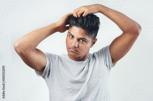 Man, portrait and haircare with grooming in studio for morning routine, getting ready or fix hairstyle. Person, serious or styling hair with space for maintenance or healthy shine on white background