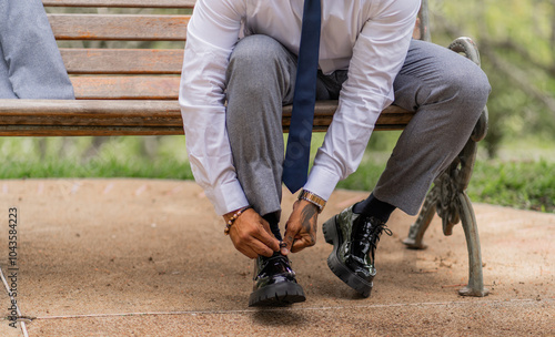 Hombre con ropa elegante se abrocha los zapatos sentado en una silla en el jardín de su casa, plano medio photo