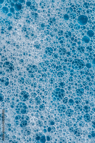 Background and pattern. White soap foam with bubbles, texture on blue tile background.