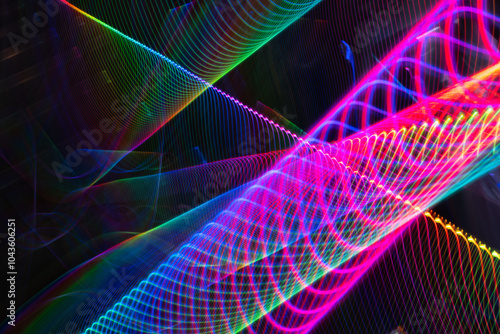 A colorful, abstract image with a rainbow of colors and a black background. The image is a representation of a wave, with the colors blending together to create a sense of movement and energy