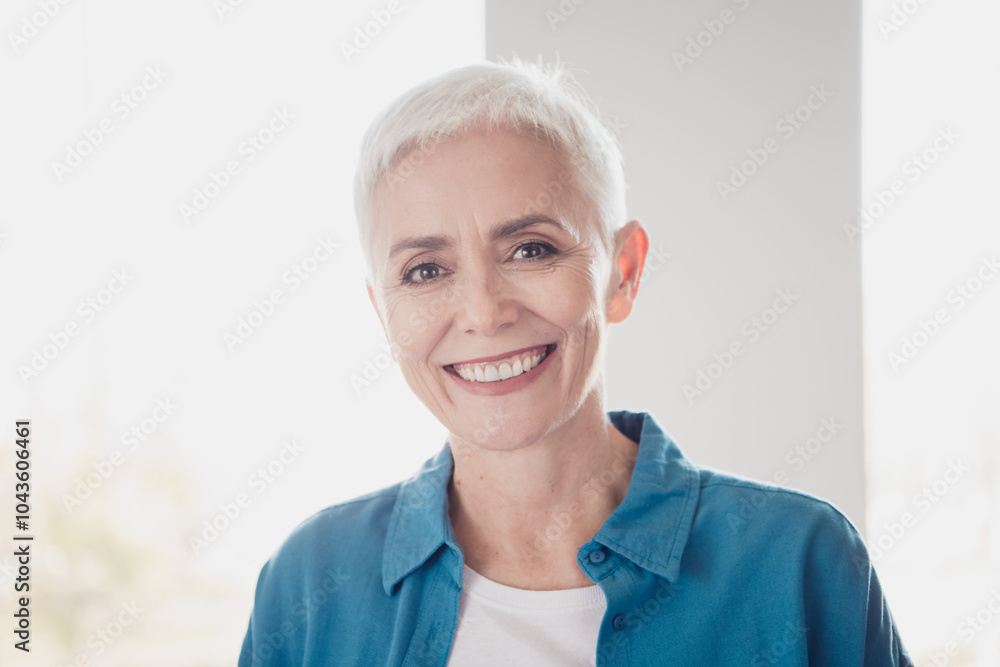 Portrait of nice aged woman beaming smile wear blue shirt bright interior flat indoors Portrait of nice aged woman beaming smile wear blue shirt bright interior flat indoors