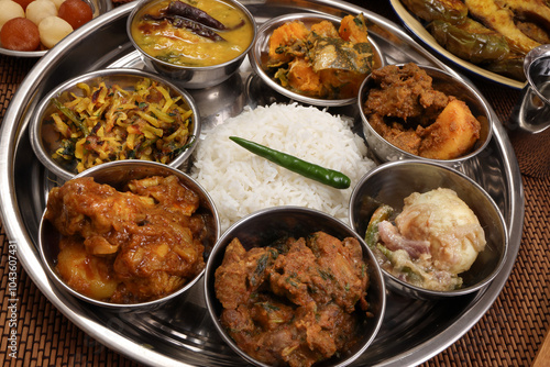 Bengali style thali spread verity cuisine hilsa fish vegetable beef mutton egg curry fry vorta mashed chicken liver sweet yogurt side dish served on rustic metal tin stainless steel plate small bowls