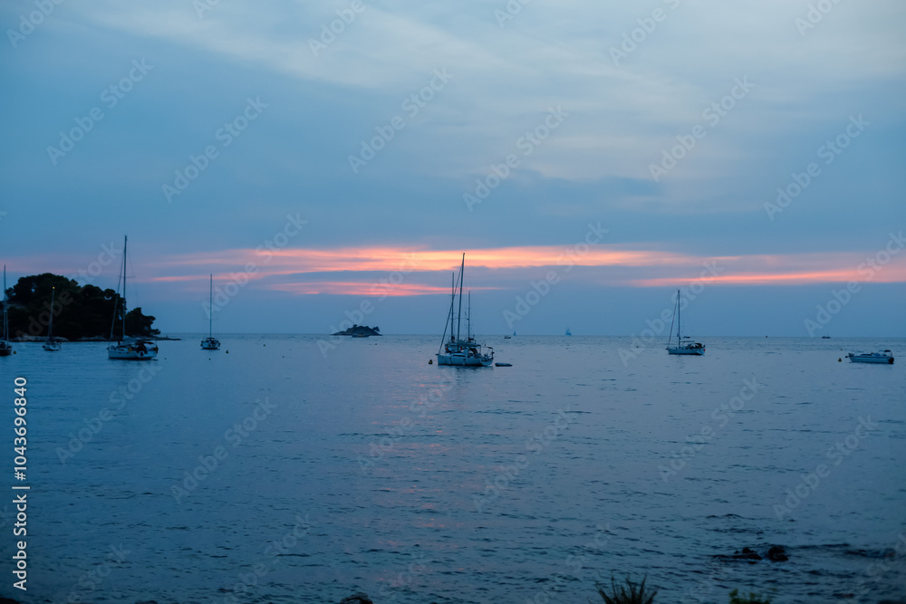 Beautiful twilight over a calm bay with sailboats anchored in tranquil waters at sunset Beautiful twilight over a calm bay with sailboats anchored in tranquil waters at sunset