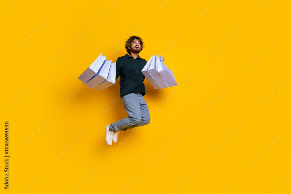 Young man jumping joyfully with shopping bags against a vibrant yellow background exciting shopping experience Young man jumping joyfully with shopping bags against a vibrant yellow background exciting shopping experience