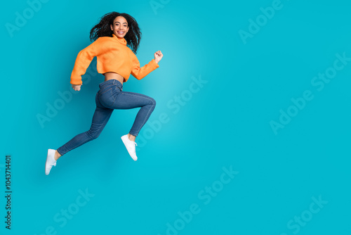 Full length photo of shiny attractive young lady dressed knitted pullover jumping high running empty space isolated blue color background