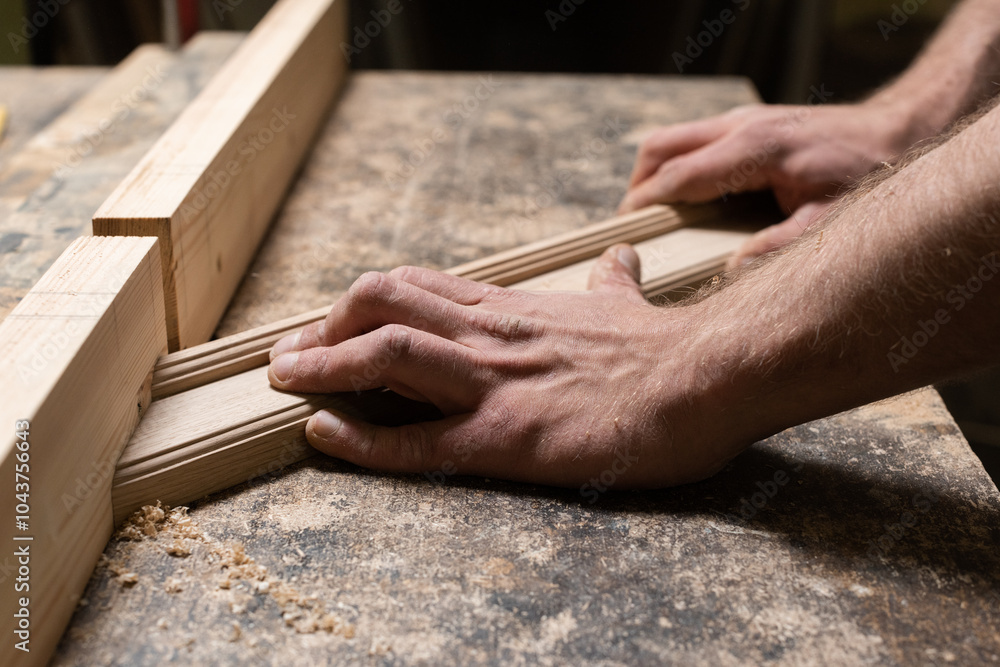 The carpenter holds an oak piece in his hands and makes a cut in it The carpenter holds an oak piece in his hands and makes a cut in it