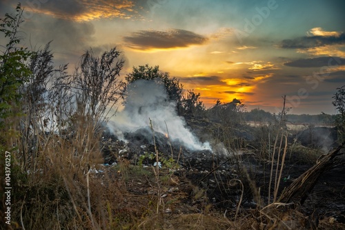 Smoke and sunset against the backdrop of a burning landfill: an ecological disaster photo