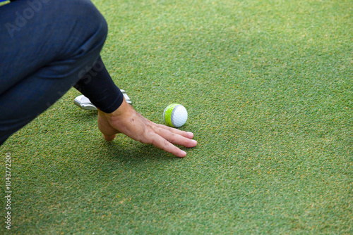 a white golf ball on a tee and a green field ready to be hit with a wood golf stick as a start to a game of golf.