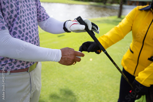 a white golf ball on a tee and a green field ready to be hit with a wood golf stick as a start to a game of golf.