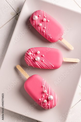 Vegan ice cream on a stick in raspberry glaze, decorated with edible pearls