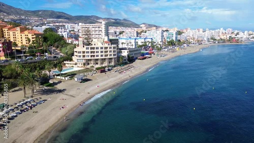 Drone flight over the Benalmadena coast overlooking the coastline, beach, residential sector and mountains in the background. 