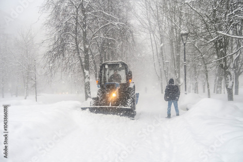 Black and white image of a heavy snowfall. Walking with a dog in bad weather on a city street. Snow storm in the city.
