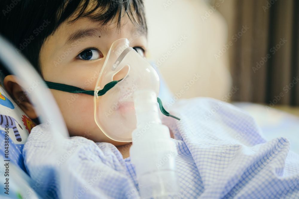 Boy 4 years old , inhale medication by inhalation mask to cure Respiratory Syncytial Virus (RSV) on hospital bed. Admitted patient boy inhalation therapy.