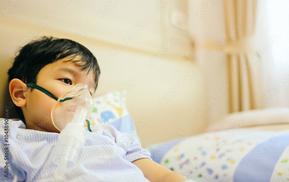 Boy 4 years old , inhale medication by inhalation mask to cure Respiratory Syncytial Virus (RSV) on hospital bed. Admitted patient boy inhalation therapy.