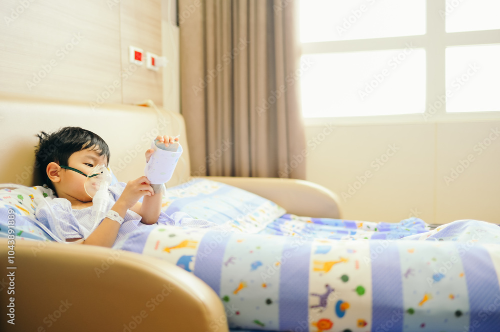 Boy 4 years old , inhale medication by inhalation mask to cure Respiratory Syncytial Virus (RSV) on hospital bed. Admitted patient boy inhalation therapy.