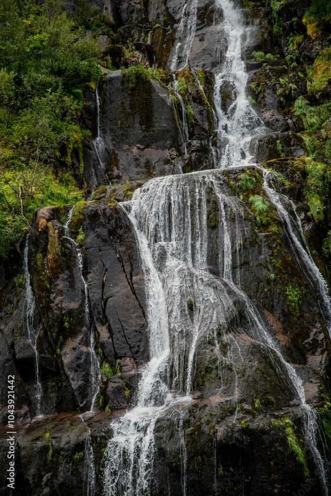 Fototapeta premium Cascading waterfall over dark rocks