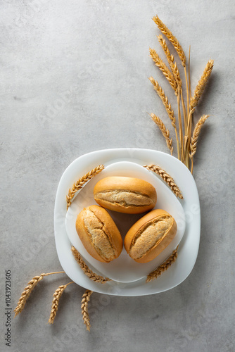 French buns and wheat ears on a marmoreal table. photo